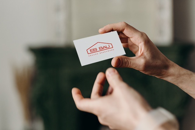 hand holding a white business card with a red logo looking like a house 