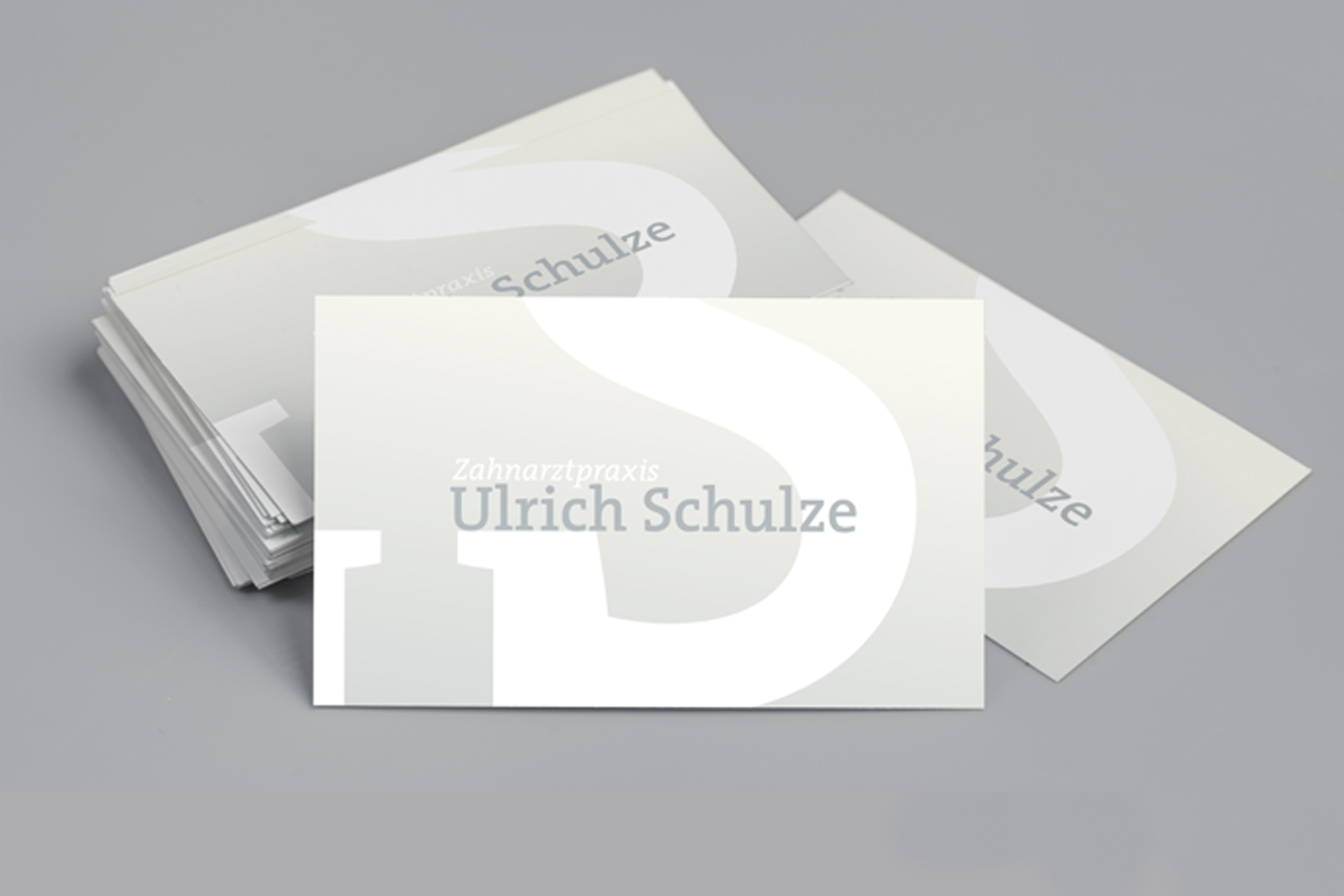stack of business cards for ulrich schulze dental practice on gray background